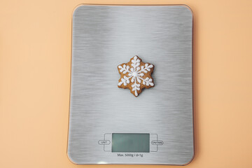 Homemade cookie. Bakery food art. Festive sweet ornament. Snowflake shaped gingerbread cookie on kitchen scales. Top view. Close-up