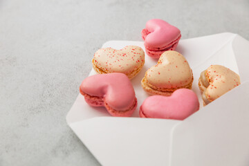 Macaron cake or heart shaped french macaroons in a postal envelope on a gray background with copy...