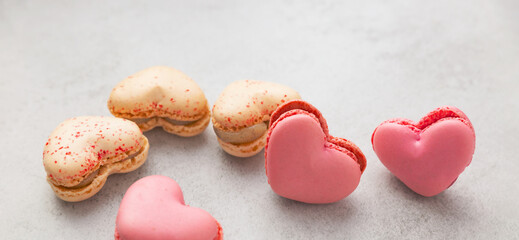 Obraz premium French meringue macaroon cookies in the shape of hearts on a gray background with copy space. Macaroons - French dessert as a gift for Valentine's Day, Mother's Day