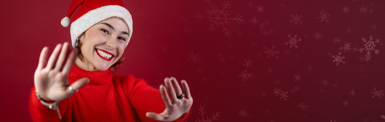Young positive woman in christmas santa hat isolated over red wall background. Happy young woman in...
