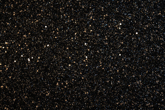 a black backgorund with glitter. a texture with golden glitter. a new year background with copy space