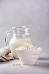 Healthy cottage cheese in white bowl with glass milk jug