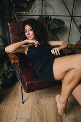Fototapeta premium Portrait of a smiling curly woman sitting in a chair