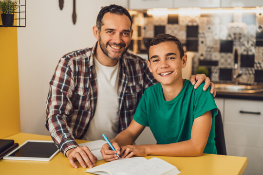 Father is helping his son with learning. They are doing homework together.