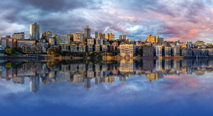 Panorama of Sydney Harbour Australia at Sunset with the reflection of the Buildings and high rise offices of the City in the water