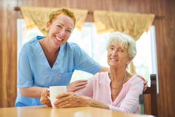 Geriatric nurse and senior woman at the table at home