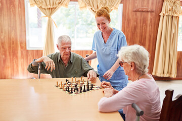 Old couple seniors playing chess in nursing home