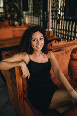 Portrait of a smiling curly woman sitting in a chair