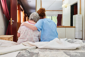 Elderly nurse hugs and comforts sick senior woman