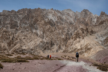 mountain trekkers walking with backpacks through the Himalayas. Raw mountain landscape with people in the background.