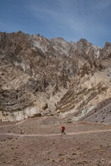 A man walking alone with a backpack in the mountains.A harsh and dry mountain landscape.