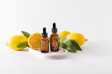 two bottles of dark glass with a dropper with cosmetic bleach stand on a plaster white tray among ripe lemons.