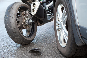 Motorcycle accident close-up view, broken parts laying on asphalt road