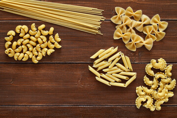 Pasta, set mix of raw maccheroni, on wooden plank dark background, top view, space to copy text.