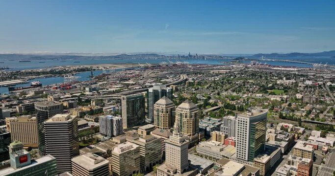 Oakland California Aerial v2 panning view fly above central business district capturing downtown cityscape, industrial shipyard and traffics on nimitz freeway - Shot with Mavic 3 Cine - April 2022