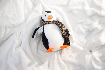 Christmas toy, penguin in a hat and a scarf in the snow