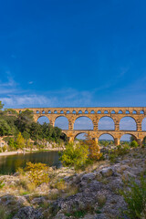 Vertical view to the orange limestone Pont du Gard three-tiered aqueduct at the river Gardon.