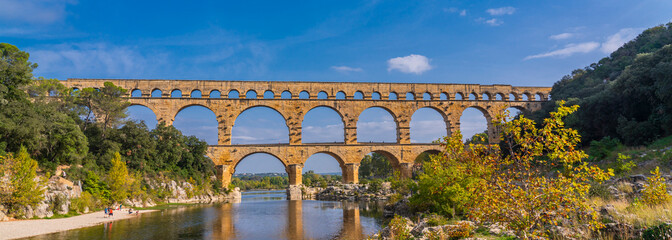 Panorama view to the limestone Pont du Gard three-tiered aqueduct at the river Gardon.
