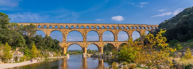 Foto op Plexiglas Pont du Gard Panoramisch uitzicht op het drieledige aquaduct van kalksteen Pont du Gard aan de rivier de Gardon.