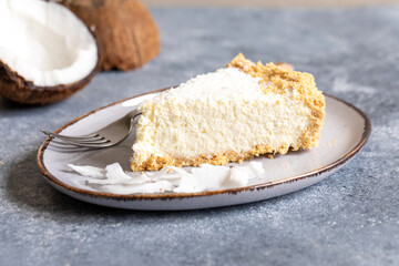 piece of coconut cheesecake on a plate with fresh coconut