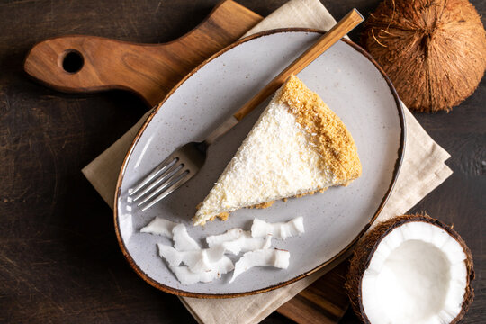 piece of coconut cheesecake on a plate with fresh coconut