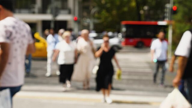 People cross the street at a crosswalk. Blurred video. Observance of traffic rules in the city. A crowd of people at a crosswalk