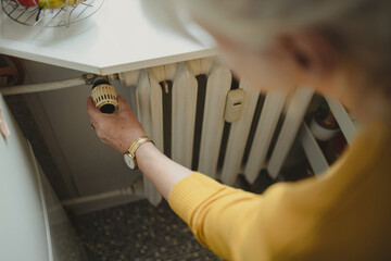 Woman adjusting the temperature of a radiator at home
