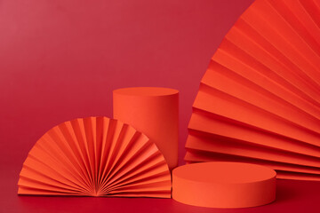 Red podiums and fans still life composition for cosmetics products. New year Valetines day holidays decorations