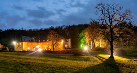 Historic castle panorama in Sundern Sauerland Germany called “Schloss Melschede“. Illuminated...