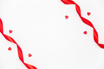 Red ribbons and decorative hearts on a white background isolated, flat lay.