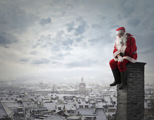 sad santa claus sitting on a chimney of a building - 551515343