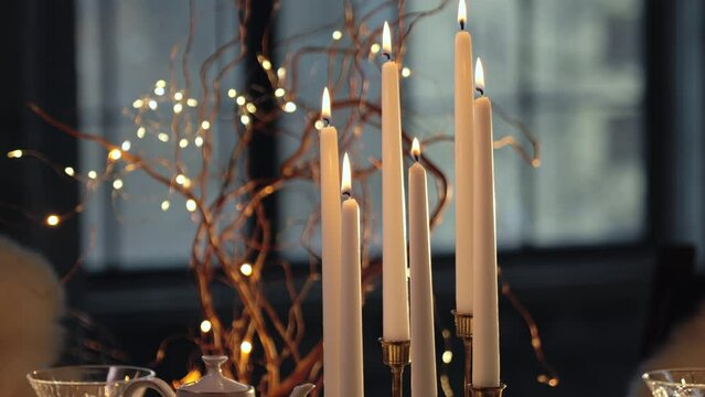 Woman hand light paraffin candles using match. Christmas table setting.