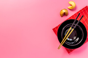 Golden chopsticks on black bowl with red napkin. Asian tabble place setting