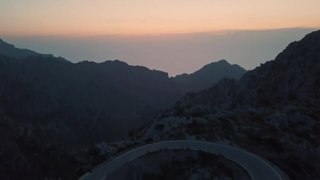 aerial view of famous road at Nus de Sa Corbata ending with a huge orange sky colour (golden hour)
