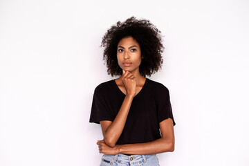 Fototapeta na wymiar Portrait of pensive young woman posing with hand on chin. African American lady wearing black T-shirt looking at camera with thoughtful expression. Thinking and planning concept