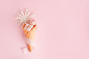 Ice Cream Cone with Christmas Decoration gift box, snowflake on pink pastel background. Minimal...