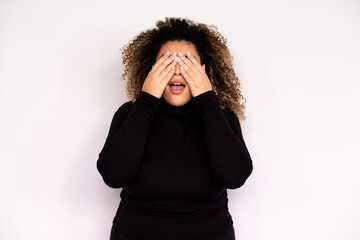 Amazed young woman closing eyes waiting for surprise. Female African American model with curly hair...