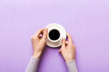 Minimalistic style woman hand holding a cup of coffee on Colored background. Flat lay, top view...