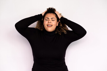 Tired young woman suffering from headache. Female African American model with curly hair and closed eyes in casual clothes holding hands on her head because of headache. Fatigue, pain concept