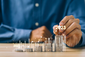Businessman draws increase arrow graph corporate future growth year 2022to 2023 on coin stacks. Concept of business growth and investment.profit, development, Planning, and success. 2023 New Year.