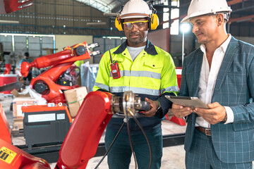 Business man and Factory engineer talking and shaking hands on business cooperation agreementAfrican American male engineer worker using tablet with the automatic robotic machine in the factory.