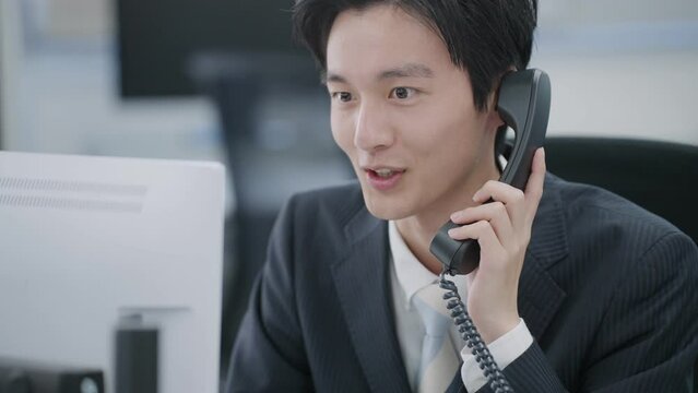 固定電話で話すビジネスマン（ビジネス・スーツ・オフィス・仕事）