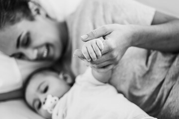 Young mother lying in bed with her son in bed at home - Focus on baby hand - Black and white editing