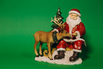 Santa's toy with a red costume and hat and a white beard and gilded glasses, isolated on a shiny orange background with bokeh. Merry Christmas