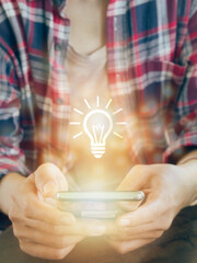 Glowing light bulb icon on smartphone. to get Business , earning money, knowledge, learning, leadership, idea, innovation and creativity concept.