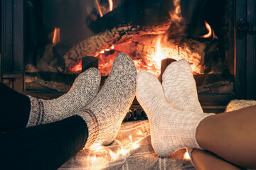 Women's feet in warm socks warm themselves by the home fireplace.