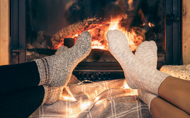 Women's feet in warm socks warm themselves by the home fireplace.