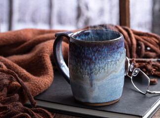 Steaming hot cup of coffee or tea by a window