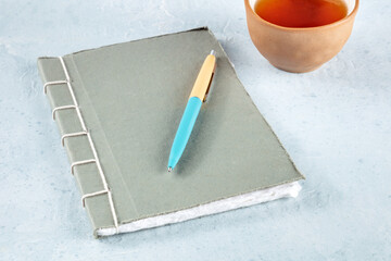 Diary. A handmade stitched journal with a pen and a cup of tea, minimalist style