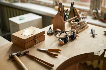 Close up of jewelers workstation with wooden table and various tools in cozy artisanal setting